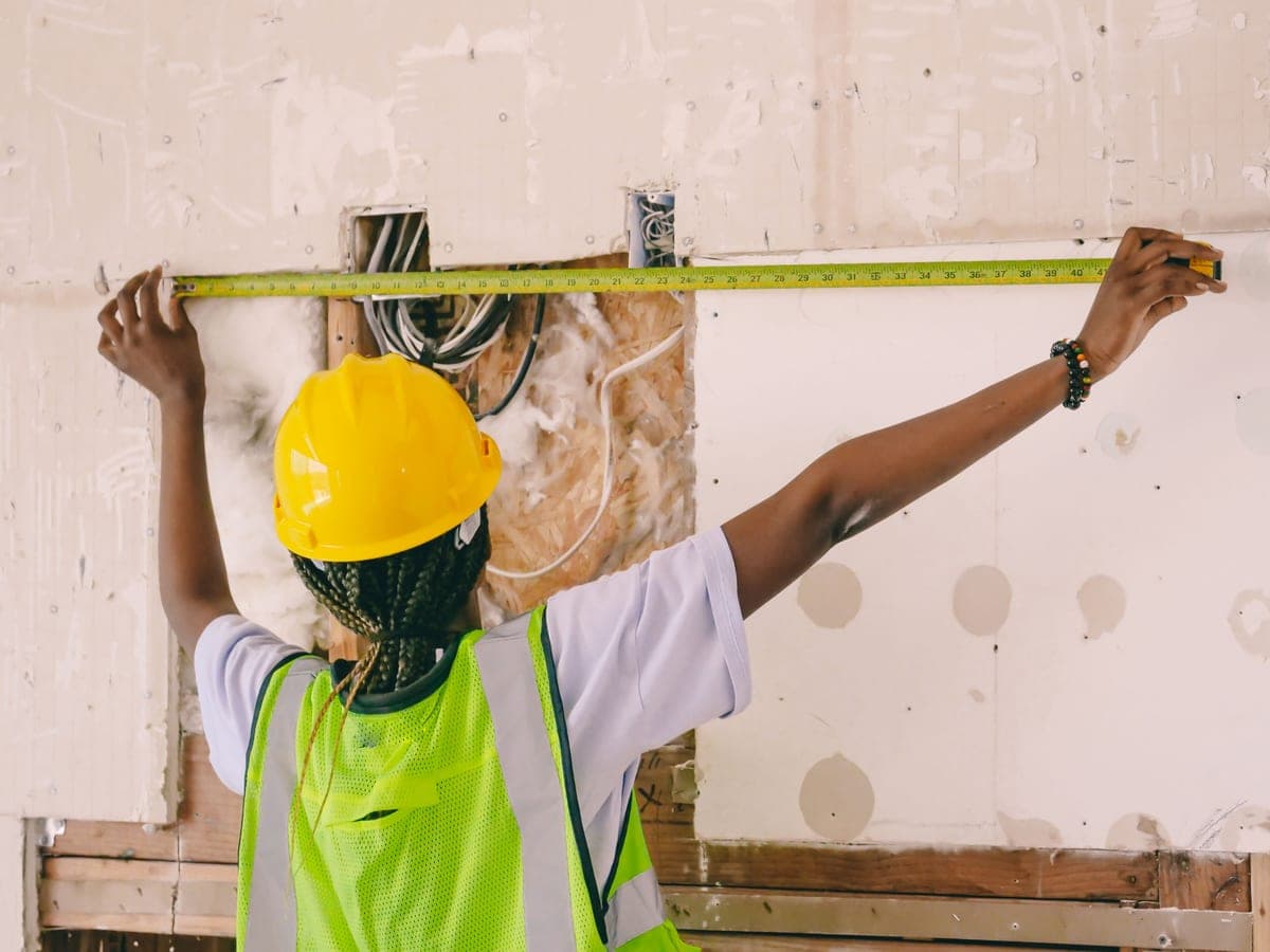 A worker measuring an interior wall with a tape measure during a fit-out