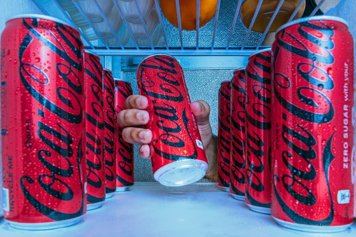 Cans of soda stacked on a refrigerator shelf