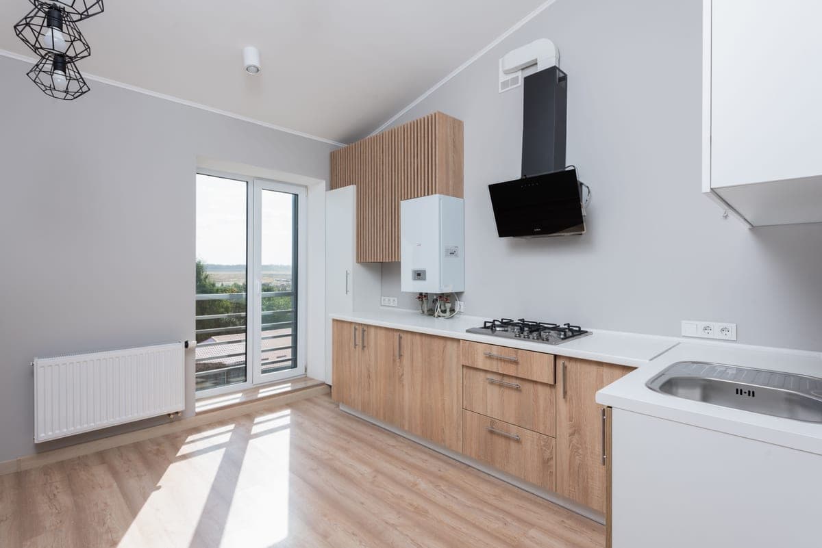 A fitted kitchen with wooden cabinetry and tall windows
