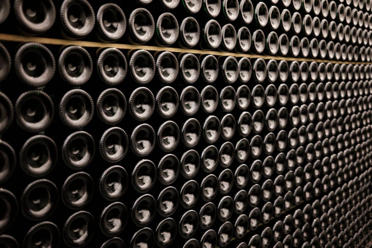 Wine bottles lying in rows in a dimly lit cellar
