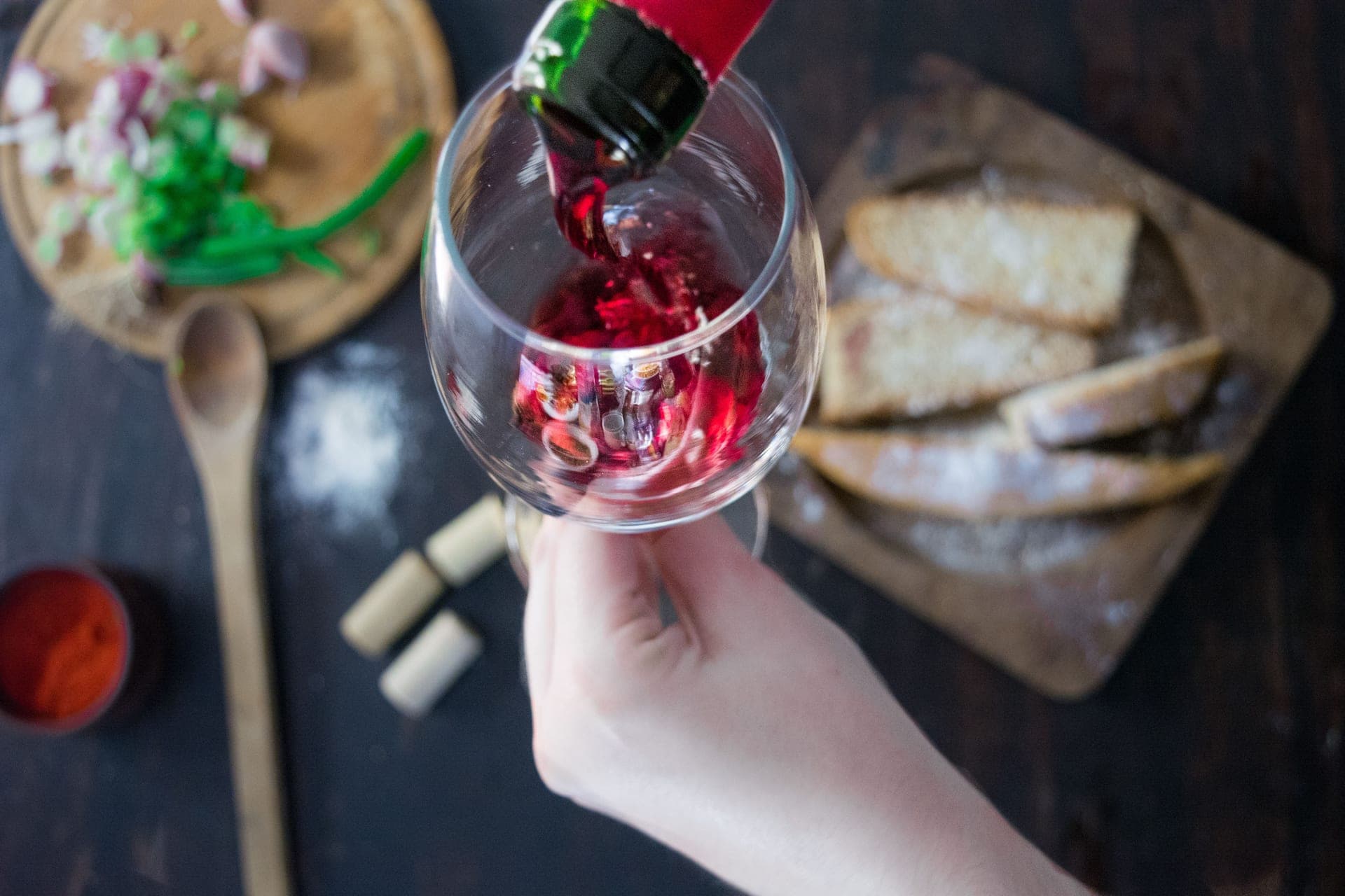 A glass of red wine being poured from a bottle