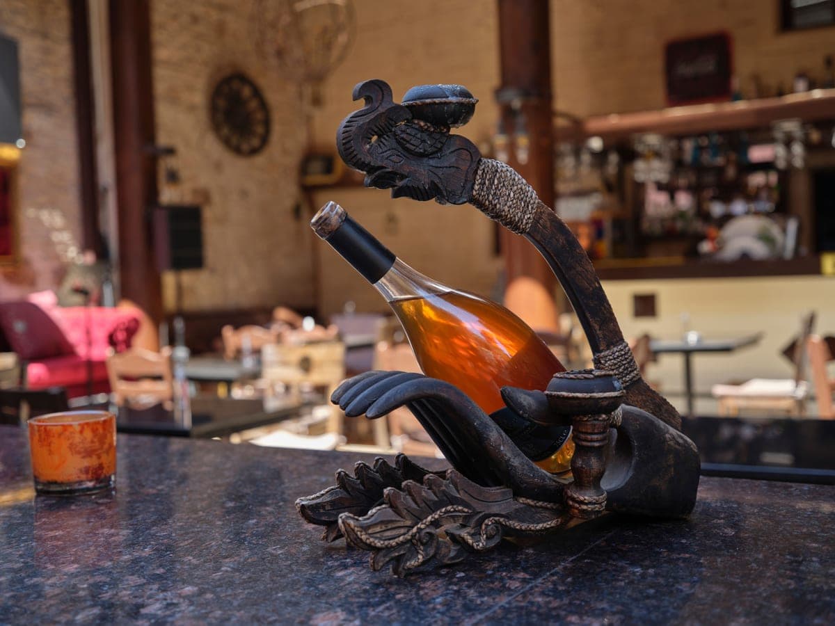 An ornate metal wine bottle holder on a stone bar counter