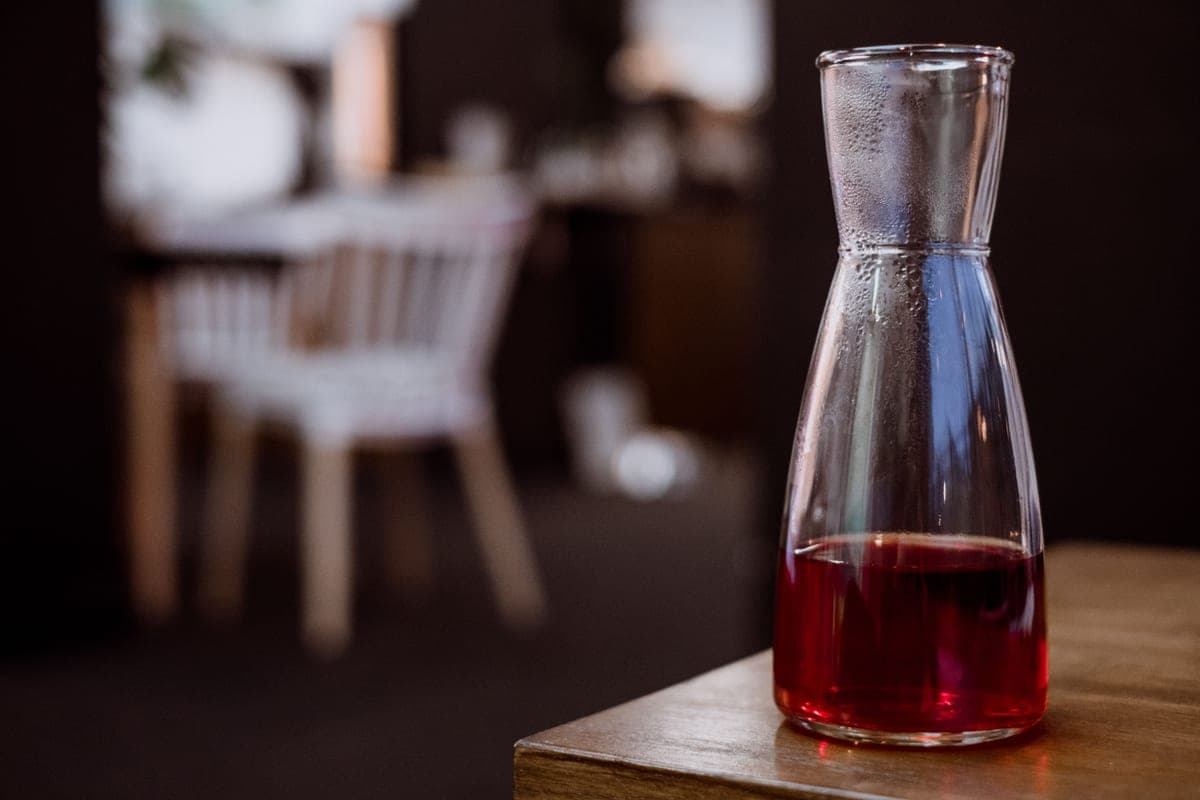 A glass carafe of red wine on a wooden table