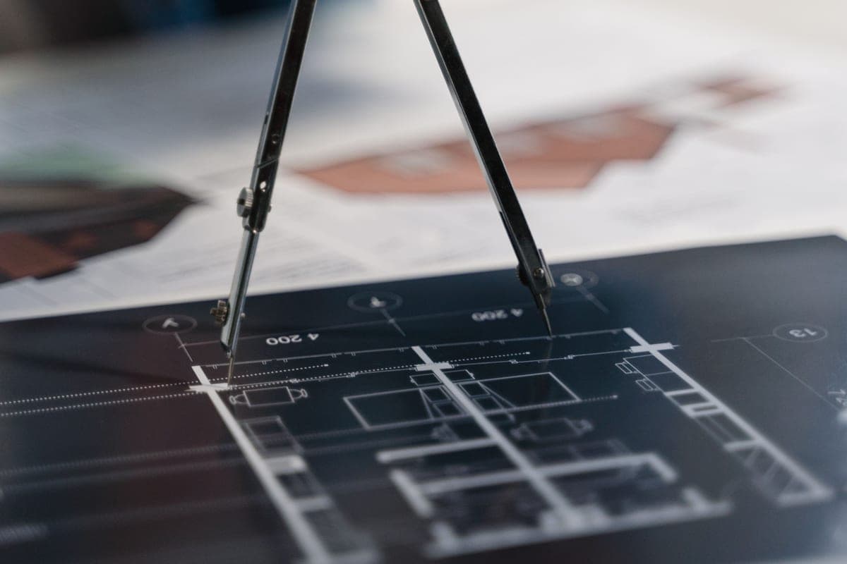 A drawing compass resting on architectural blueprints