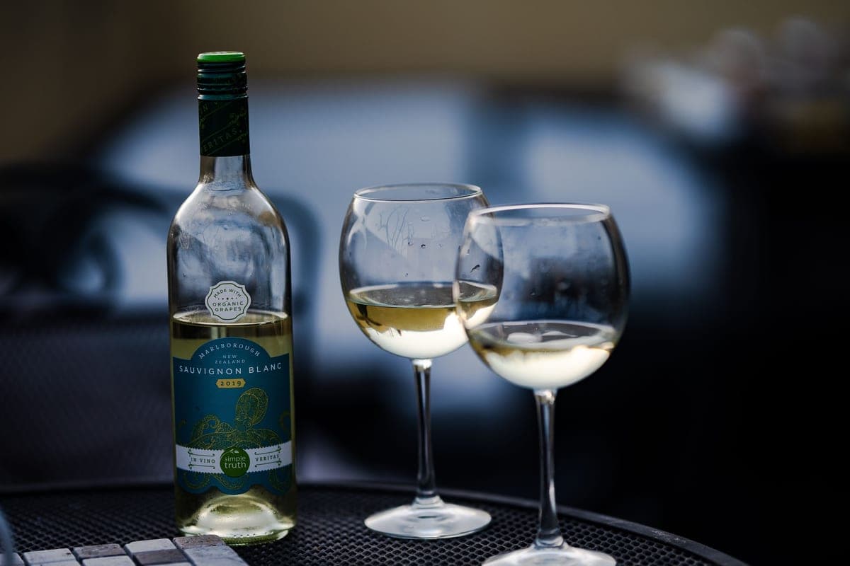An open bottle of wine and a glass on a table in the evening