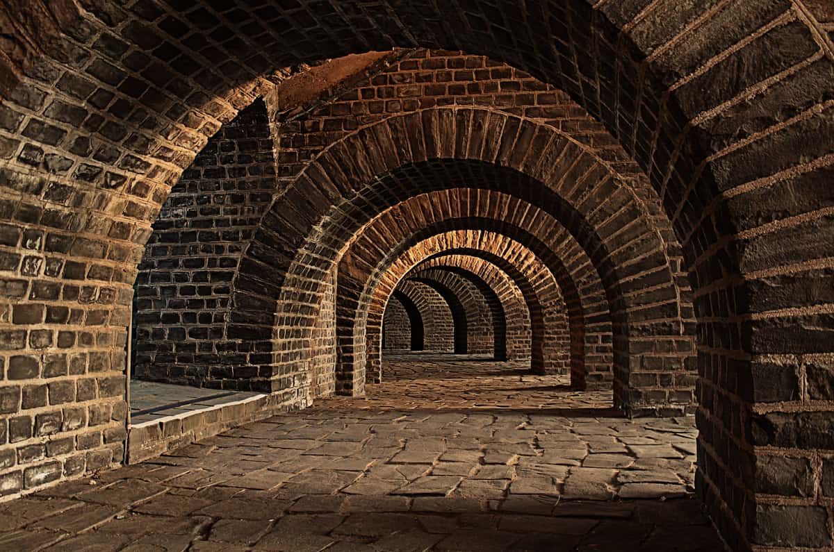 A stone vaulted cellar lined with wine bottles