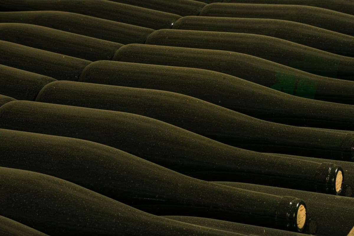 A collection of wine bottles being counted on a shelf