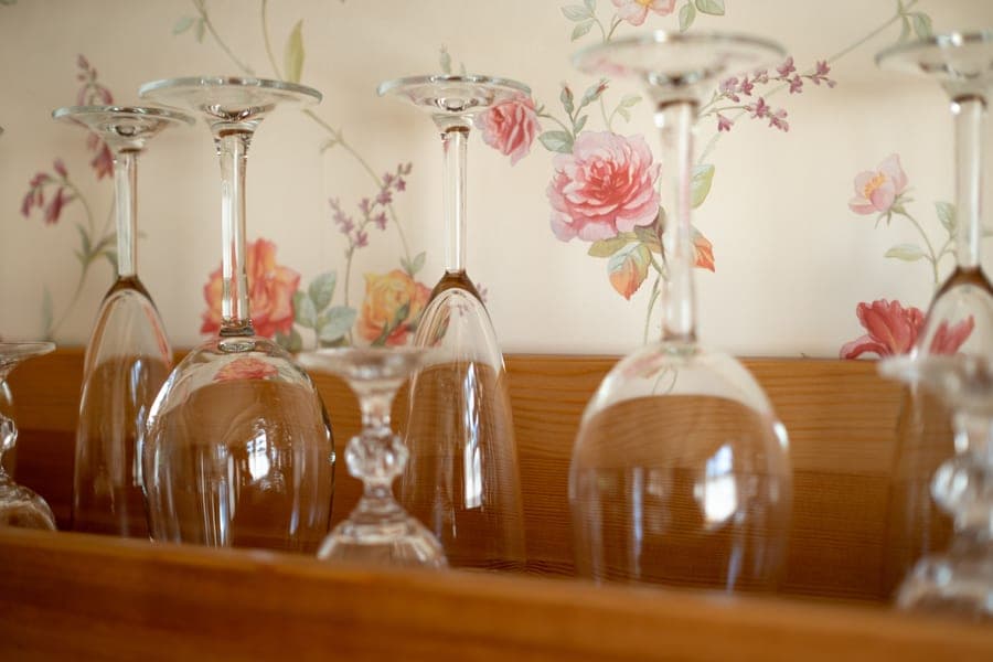 Wine glasses hanging from a rack beneath a kitchen cabinet