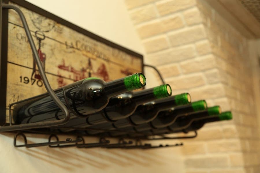 A wall-mounted wooden rack holding wine bottles horizontally